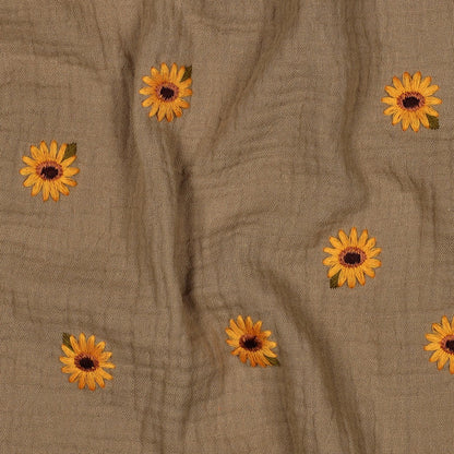 Detailaufnahme des sandfsrbenen Musselinstoffes mit den gestickten Sonnenblumen