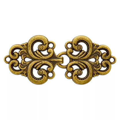 Zweiteiliger Metallverschluss in Altmessing mit geschwungenen Ornamenten, mittigem Haken und seitlichen Annähösen auf weißem Hintergrund.